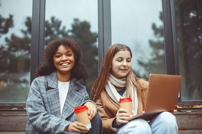 Female friends with coffee sitting on steps