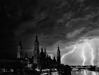 Illuminated cityscape against cloudy sky