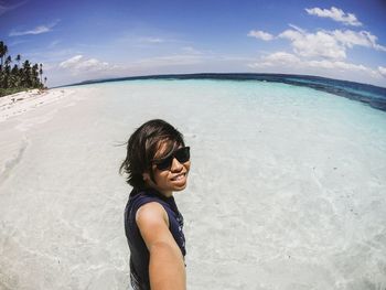 Young woman smiling on beach against sky