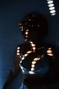 Sensual woman standing by wall in darkroom