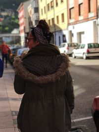 Rear view of woman wearing fur coat walking on city street