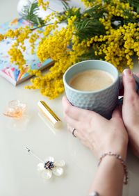 High angle view of hand holding coffee cup on table