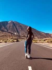 Rear view of woman looking away while standing on road