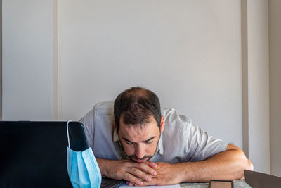 Frustrated man wearing flu mask sitting at office