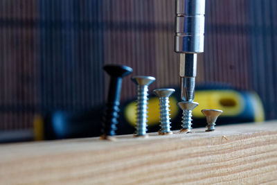 Close-up of screwdriver fixing nail in wood