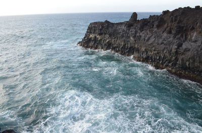 Rock formation in sea against sky