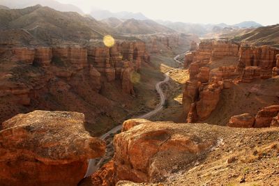 The road in the charyn canyon in the summer at sunset, around the mountain ranges and peaks