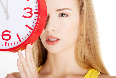 Woman holding wall clock against white background