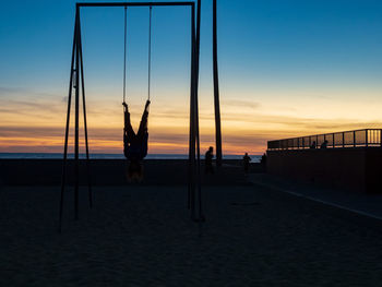 Silhouette people on beach against sky during sunset