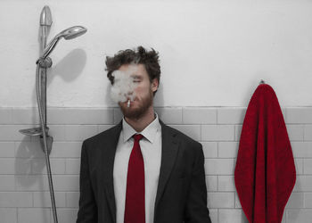 Portrait of young man standing against wall