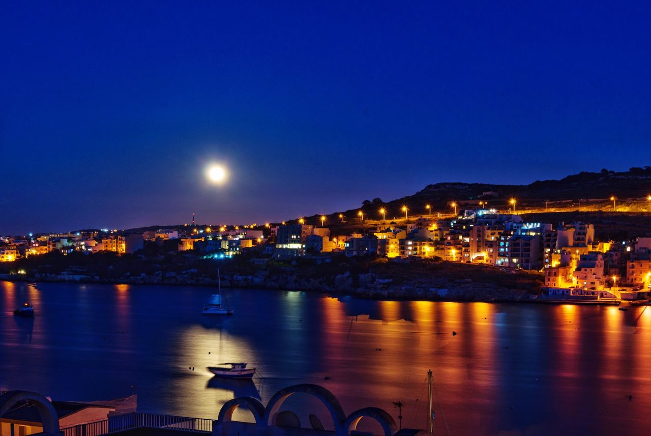 Illuminated cityscape against clear sky at night