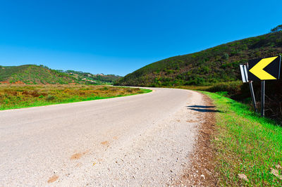 Road by mountain against clear blue sky