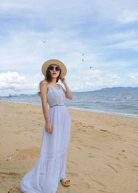 Woman standing at beach against sky