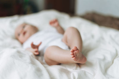 Cute baby girl 2-4 month on bed with white linen, the natural tones, selective focus