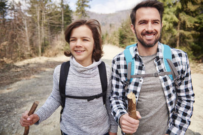 Father and son hiking against trees