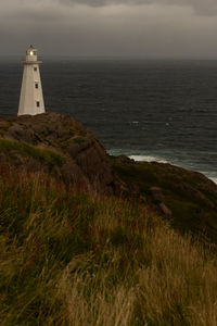 Lighthouse by sea against sky