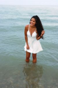 Smiling young woman standing in sea