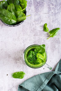 Green spinach smoothie in a glass on a gray background. healthy food. top and vertical view