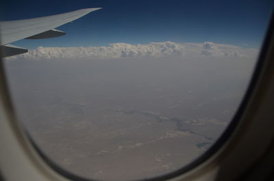 Airplane flying in sky seen through glass window