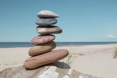 Stack of pebbles on beach against sky