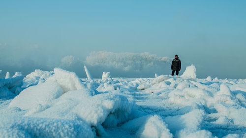 Man standing on snow covered land against sky