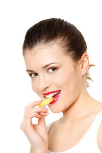 Portrait of young woman eating apple against white background