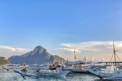 Boats moored at harbor against sky