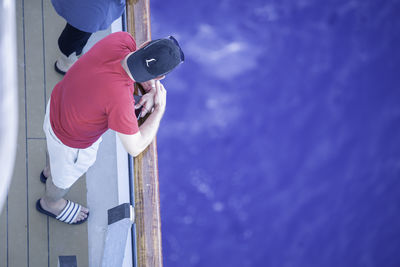 Side view of man photographing against blue sky