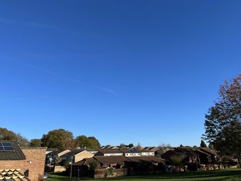 Houses and trees against clear blue sky