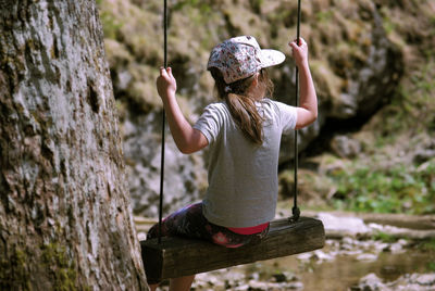 Rear view of girl swinging in park