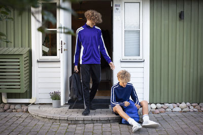 Brothers in sports clothing at house doorway