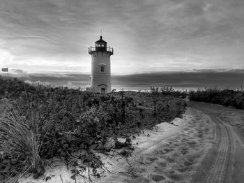 Lighthouse on landscape against cloudy sky