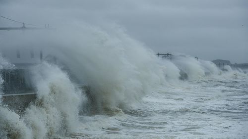 Waves splashing in sea against sky