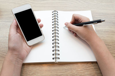 High angle view of person using mobile phone on table