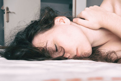 Close-up of woman lying on bed at home