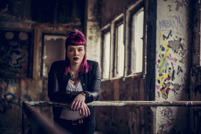 Portrait of woman standing by railing in abandoned building