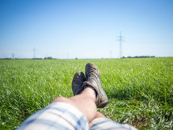 Low section of man lying on field against clear sky