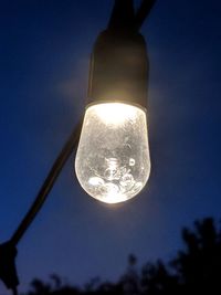 Low angle view of illuminated light bulb against blue sky