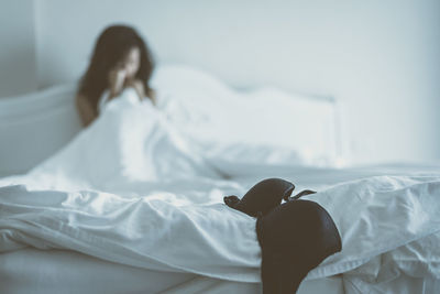 Terrified woman sitting on bed with bra in foreground