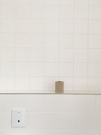 Close-up of brown toilet paper against white tiled wall in bathroom