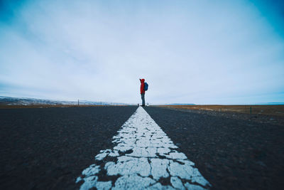 Side view of man standing on road against sky