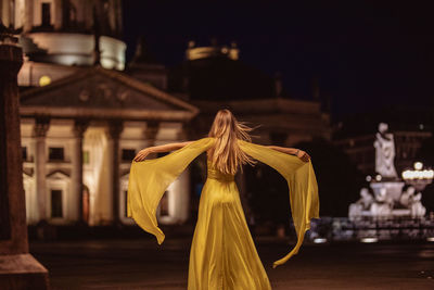 Rear view of woman standing in city at night