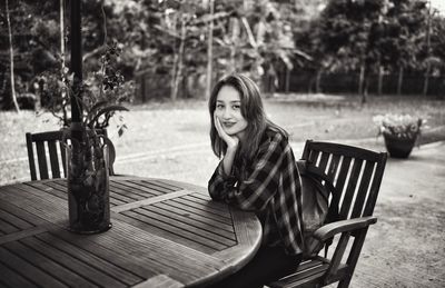 Portrait of smiling young woman sitting on table