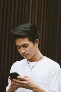 Young man using mobile phone while standing outdoors