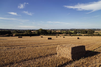 Hay bales on field against sky