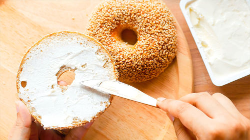 Cropped hand of person holding donut on table