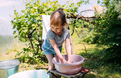 Little preschool girl helps with laundry. child washes clothes in garden