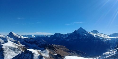 Scenic view of snowcapped mountains against blue sky