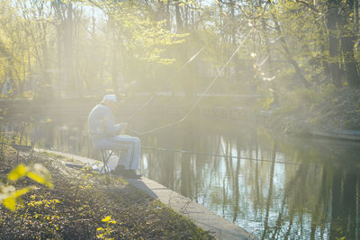 Side view of man sitting by lake