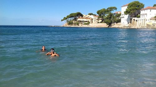 Men swimming in sea against sky